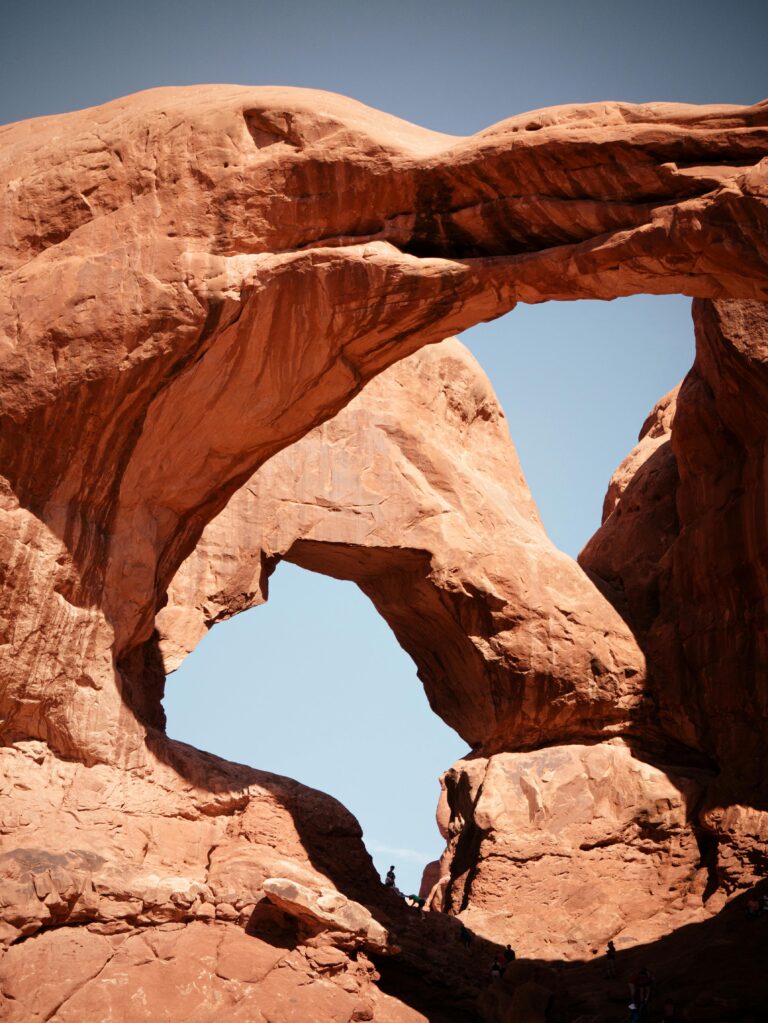 Dramatic red rock formations in Arches National Park against a clear blue sky.