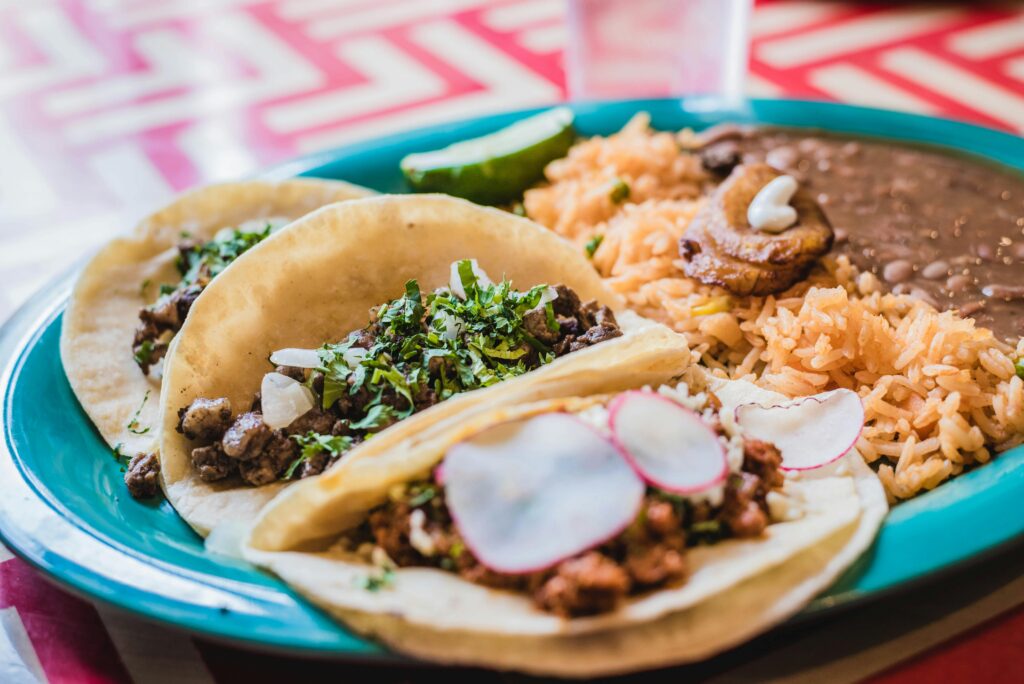 Close-up of delicious Mexican tacos with beans and rice, vibrant and tasty meal.